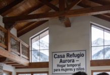 —Hemos oído que te has comprado una villa de lujo en los Alpes. Hemos venido a vivir contigo y hacer las paces —declaró Lucía, mi nuera, empujando la primera maleta dentro, como si la casa ya fuera suya. Yo no me aparté. Simplemente di un paso hacia atrás, dejando la puerta abierta. Detrás de ella, Javier evitaba mi mirada, con las manos ocupadas en dos maletas más. Marta y Diego, mis nietos, tiritaban de frío en el porche, con las mejillas rojas y los ojos curiosos clavados en el interior de la casa. Hacía tres años que no los veía. Tres años desde aquella discusión en Madrid, cuando vendí el piso familiar después de que Antonio muriera y me negué a “prestarles” la mitad del dinero para tapar los agujeros del estudio de arquitectura de Javier y los caprichos de Lucía. “Egoísta”, me gritó ella entonces. “Si te vas, no vuelvas a llamarnos”, respondió él, con la mandíbula apretada. Y lo cumplieron. Hasta hoy. —Vaya vistas… —murmuró Javier, entrando por fin y mirando a través de los ventanales hacia las montañas nevadas—. No está mal, mamá. No dijo “hola”. No dijo “¿cómo estás?”. Sólo evaluó la casa, como si fuese otro proyecto inmobiliario. Lucía sonrió con una cordialidad tensa, esa sonrisa suya que siempre escondía algo. —Sabemos que aquí tienes espacio de sobra —continuó, quitándose el abrigo caro que ya mostraba los hilos sueltos—. En Madrid… bueno, las cosas se han puesto difíciles. Pensamos que podría ser bueno para todos empezar de cero. En familia. “En familia”, repitió mi cabeza, saboreando la ironía. Ellos creen que han venido a colonizar mi refugio, pensé. No tienen ni idea de lo que he hecho con esta casa. —Mamá, por lo menos podrías decir algo —saltó Javier, quizá molesto por mi silencio. —Hace frío —respondí al fin—. Entrad. Cerrad la puerta. Diego se adelantó corriendo por el pasillo, seguido de Marta. Recordaba vagamente la distribución mejor que ellos: las fotos que había subido una vez a aquel chat familiar muerto. El suelo de madera crujió bajo sus zapatillas húmedas. El olor a chimenea, a sopa recién hecha y a detergente llenaba el aire. Lucía pasó a mi lado rozándome el brazo, como si el contacto físico fuera una declaración de victoria. —Te prometo que esta vez todo será distinto —susurró—. Venimos en son de paz. No contesté. Sólo los guié hacia el fondo del pasillo, donde dos puertas dobles de cristal abrían al gran salón principal. El corazón empezó a latirme más fuerte. Ellos todavía no sabían que esta villa no era exactamente el palacio vacío que imaginaban. Empujé las puertas. El salón, con su techo alto de vigas vistas, estaba inundado de luz. Una larga mesa de madera ocupaba el centro, cubierta de tazas de café, cuadernos, lápices de colores. En un rincón, dos mochilas escolares apoyadas contra la pared. Unas botas de mujer secándose junto a la chimenea. Y sobre la repisa, un cartel hecho a mano, con letras cuidadas: “Casa Refugio Aurora – Hogar temporal para mujeres y niños”. Cinco mujeres se volvieron a la vez hacia nosotros, interrumpidas en su conversación. Dos niños pequeños dejaron de jugar con un puzle en la alfombra. El silencio cayó como un peso. Lucía se quedó clavada en el umbral, pálida. —¿Qué… es esto? —susurró. Javier miró a las mujeres, luego a mí, con los ojos muy abiertos. Yo sentí cómo todas las miradas de la sala se clavaban en mi rostro cuando una de las mujeres, Ana, se levantó despacio de la mesa… y pronunció las palabras que helaron aún más el ambiente: —Carmen, nos dijiste que aquí no entraría nadie que no fuera parte del refugio. Todos se quedaron congelados en el sitio.
